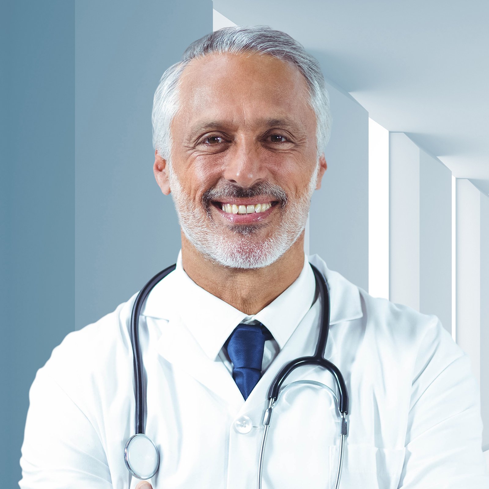 Male doctor standing with arms crossed in corrirdor
